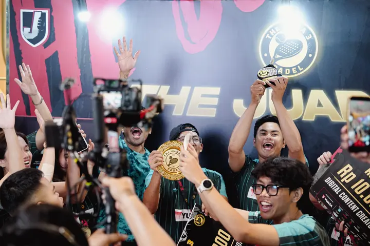Winners lifting the trophy in front of the media wall